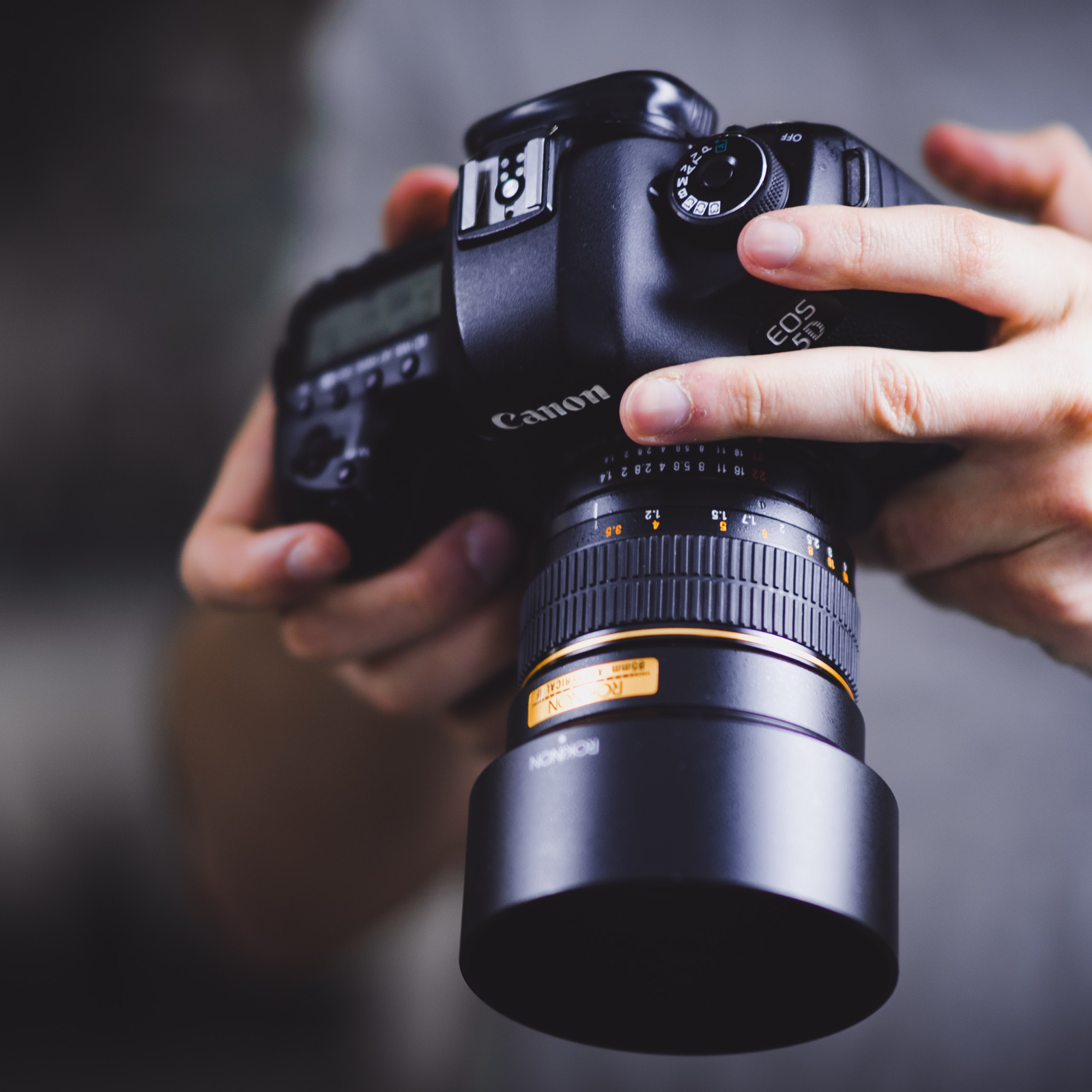 Human hands holding a Canon camera