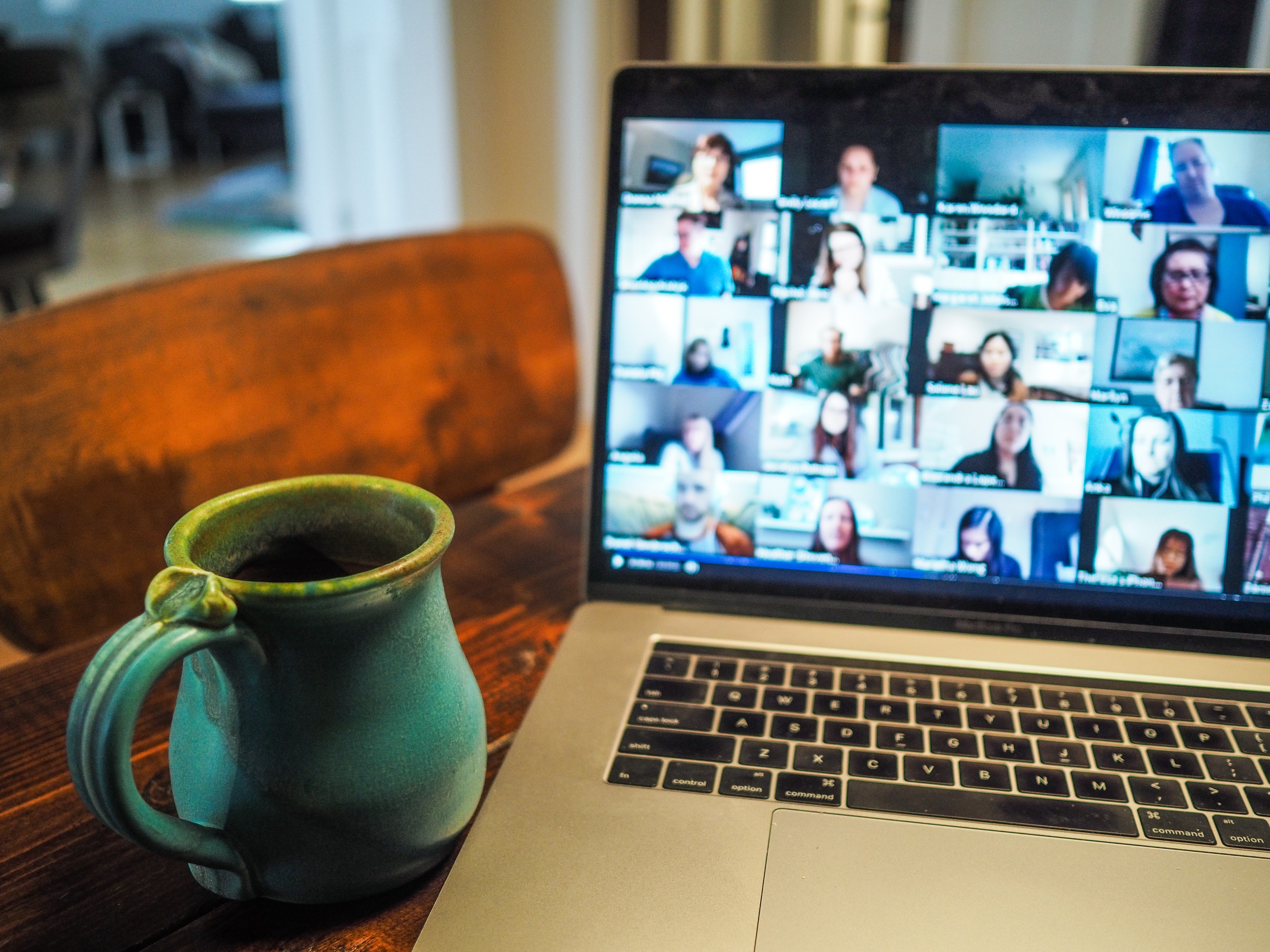 Open laptop with a multi-person video conference call taking place, and a mug of coffee in the foreground