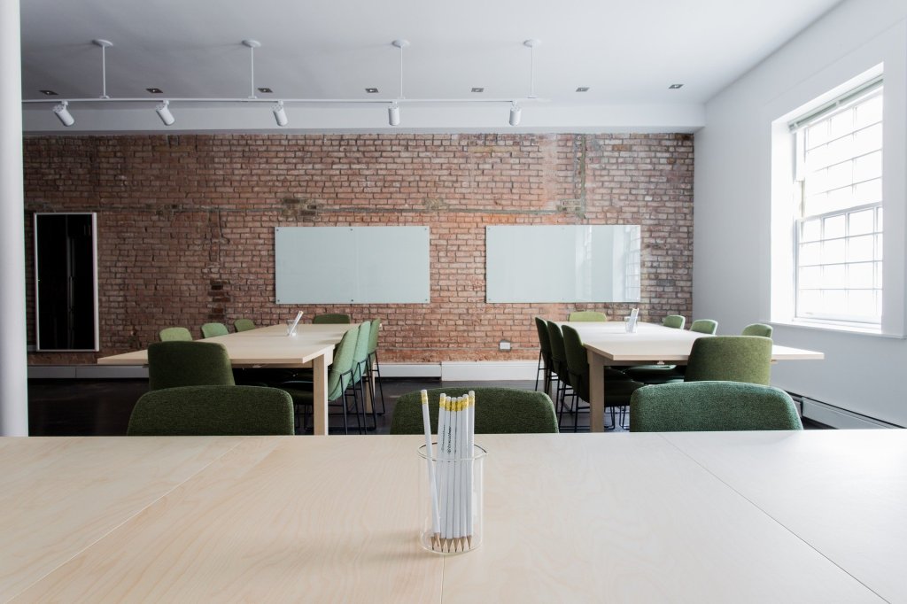 Empty business space with chairs, tables, glass whiteboards, and pencils in a glass in the foreground
