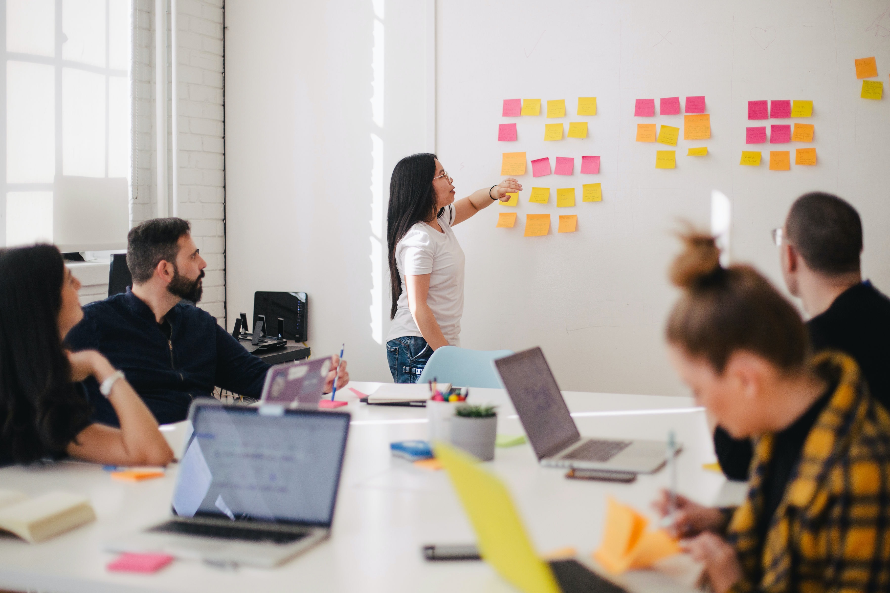 Participants in a workshop, looking at a wall with post-it notes on it