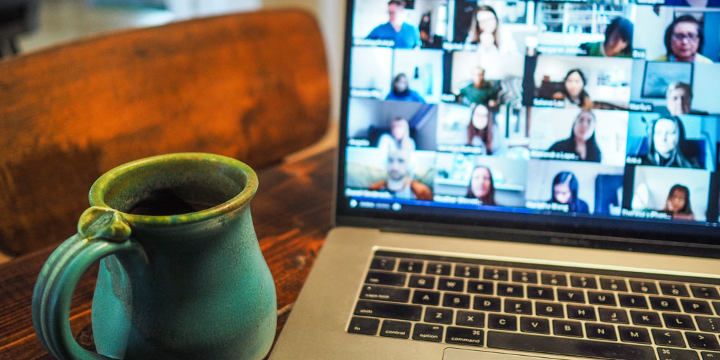 Open laptop with a multi-person video conference call taking place, and a mug of coffee in the foreground