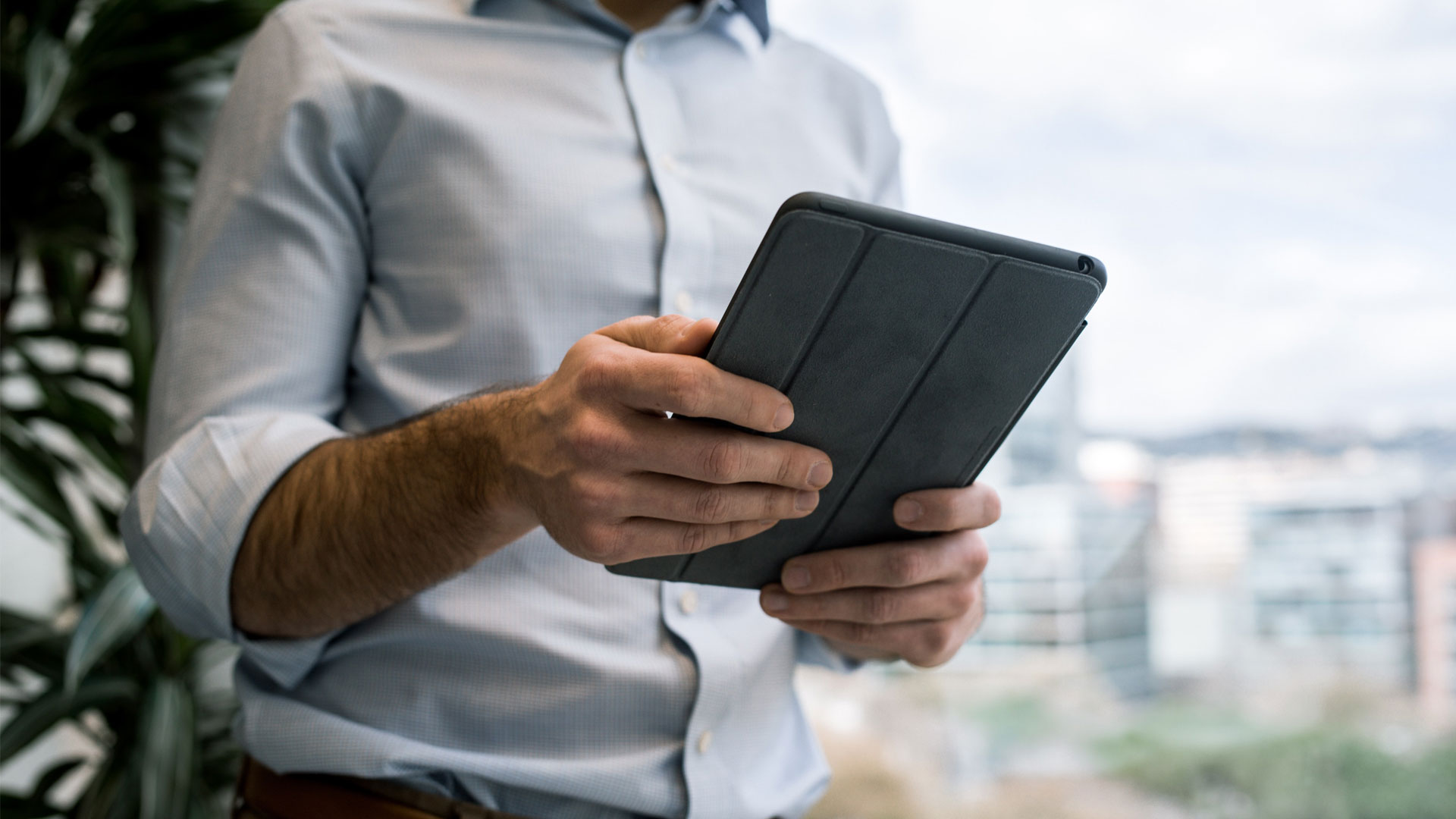 Man using iPad, shown from the neck down