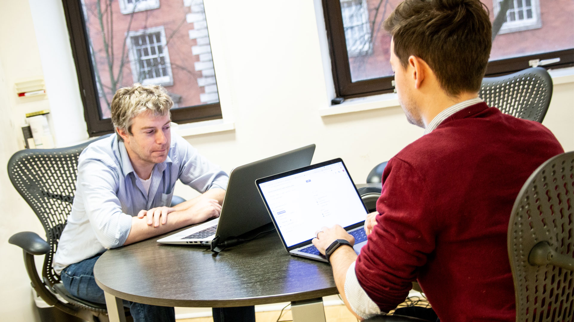 Two people working on laptops at a table