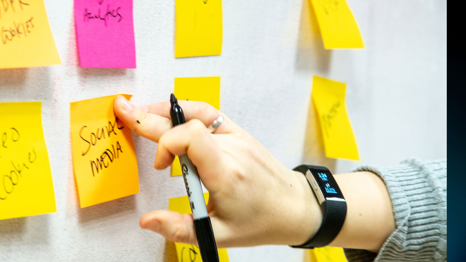 Person putting a post-it note saying 'social media' on a wall