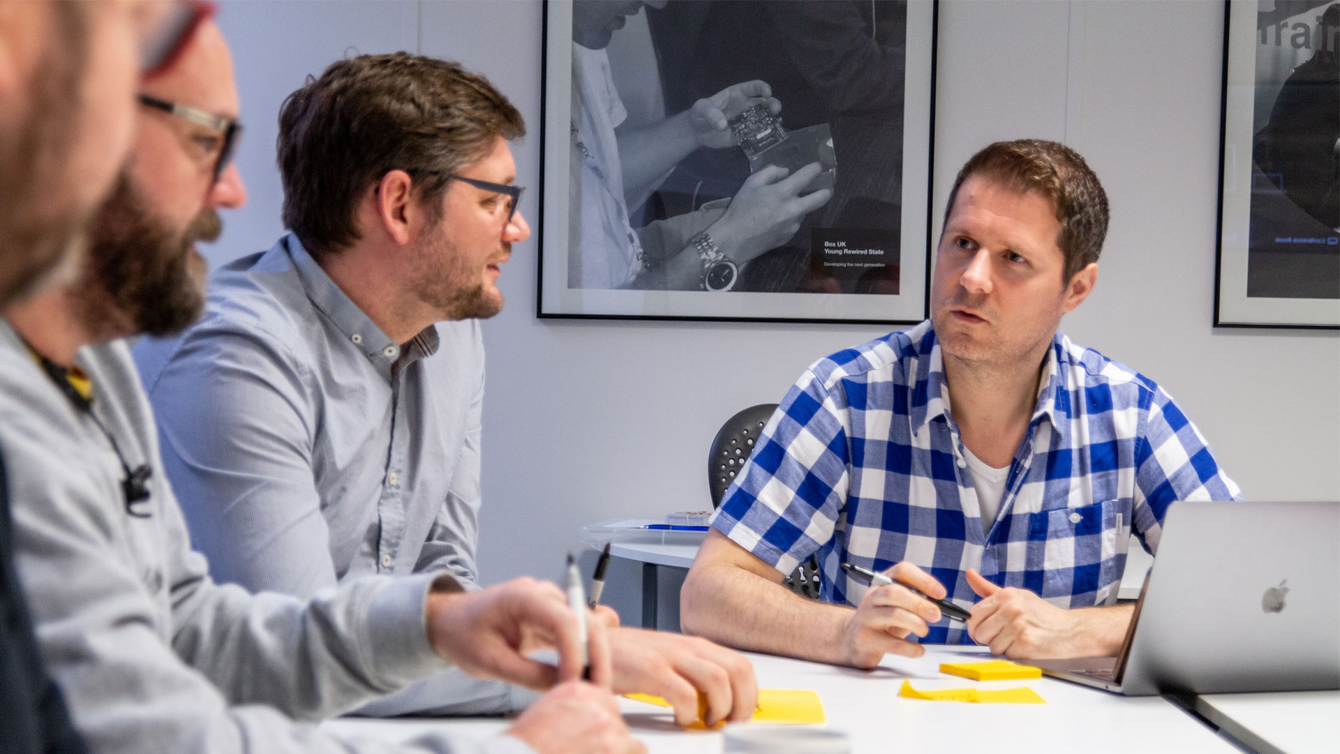 Group of people discussing around a table, with pens and post-it notes