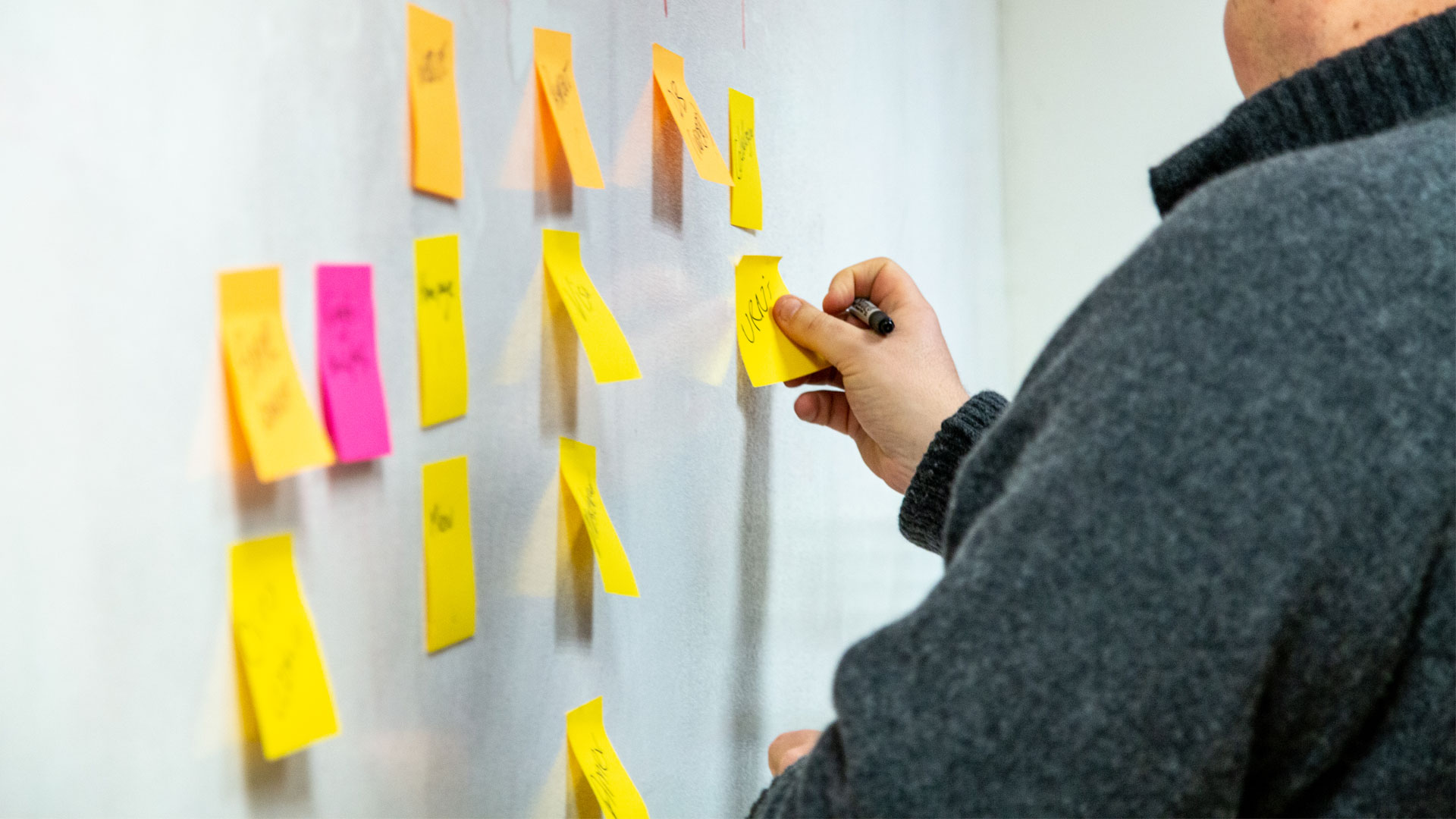 Person sticking post-it notes to a wall