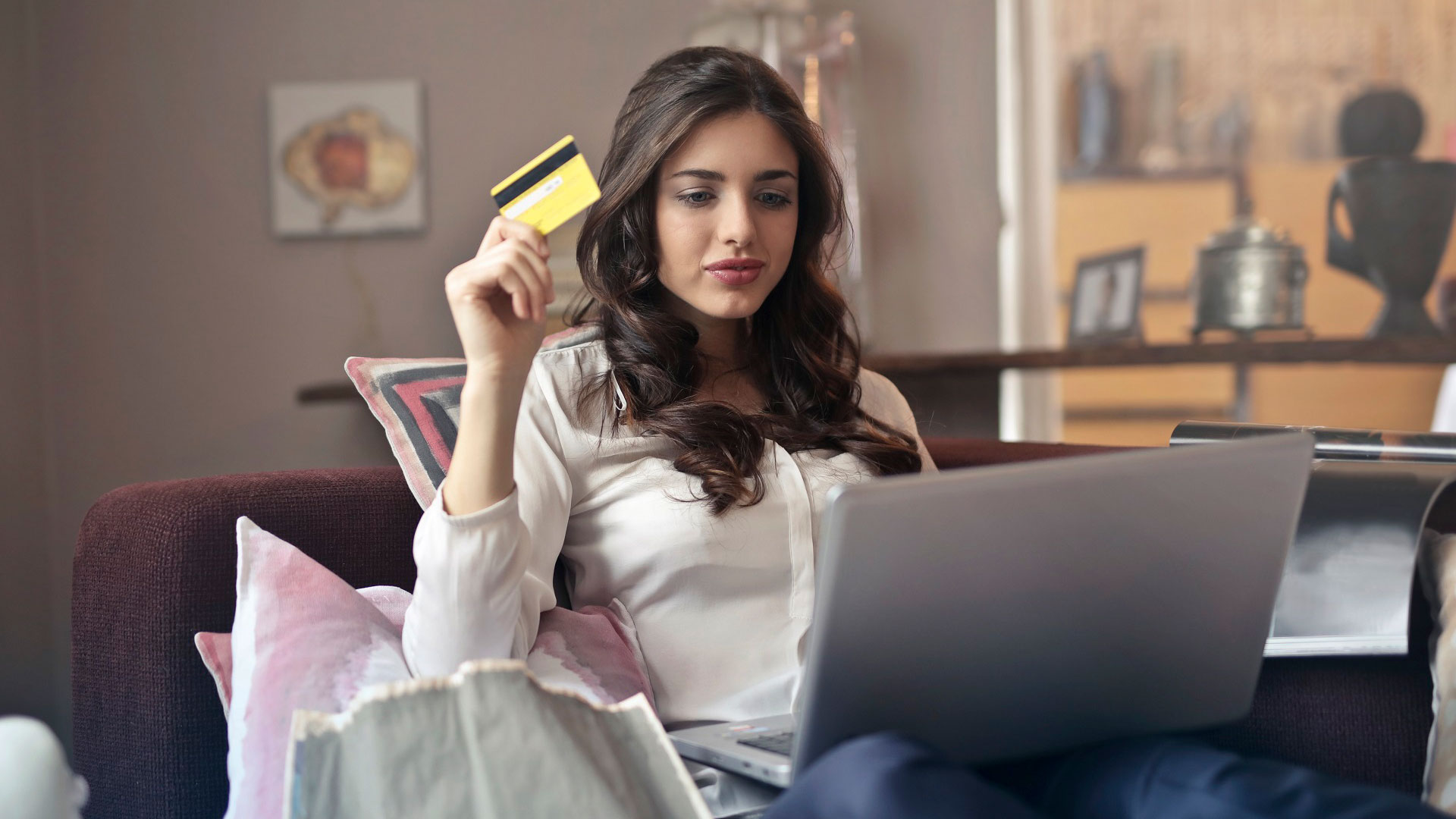 Woman on sofa with laptop, holding a credit card