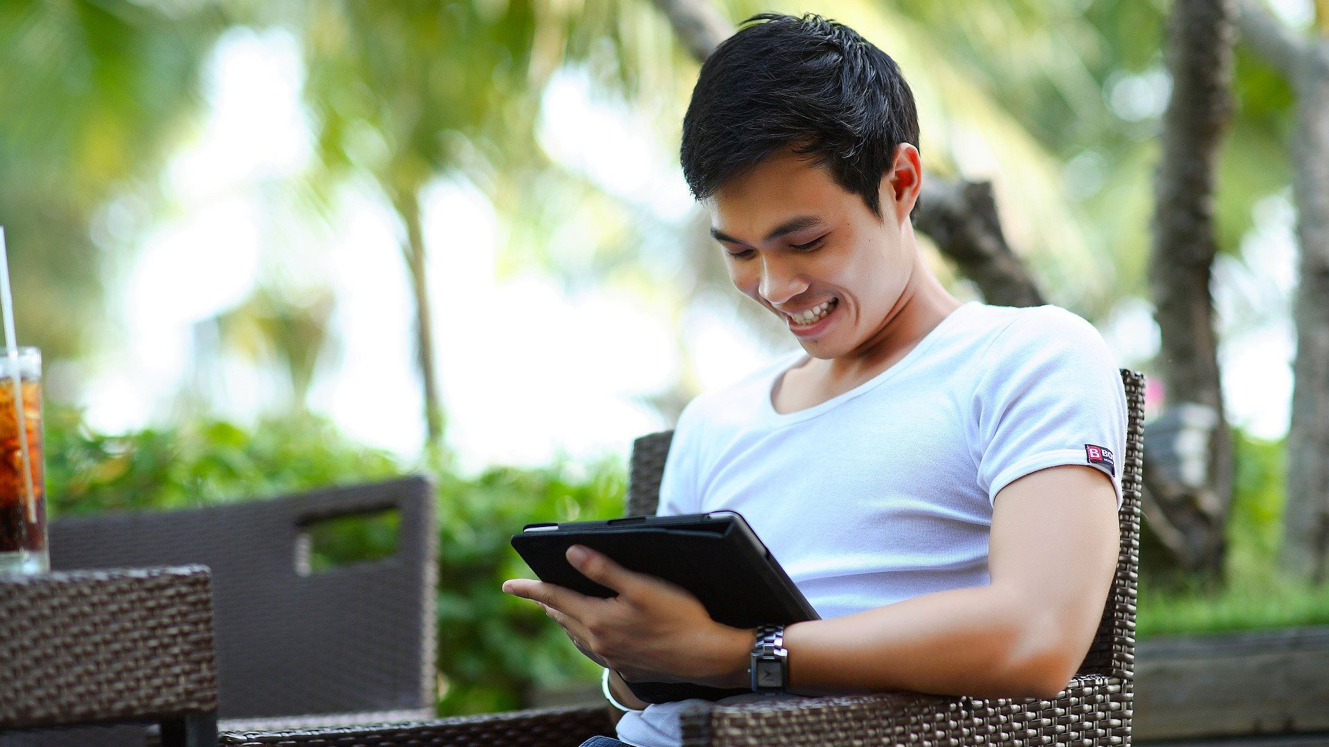 Man sat on a chair outside, using a tablet device