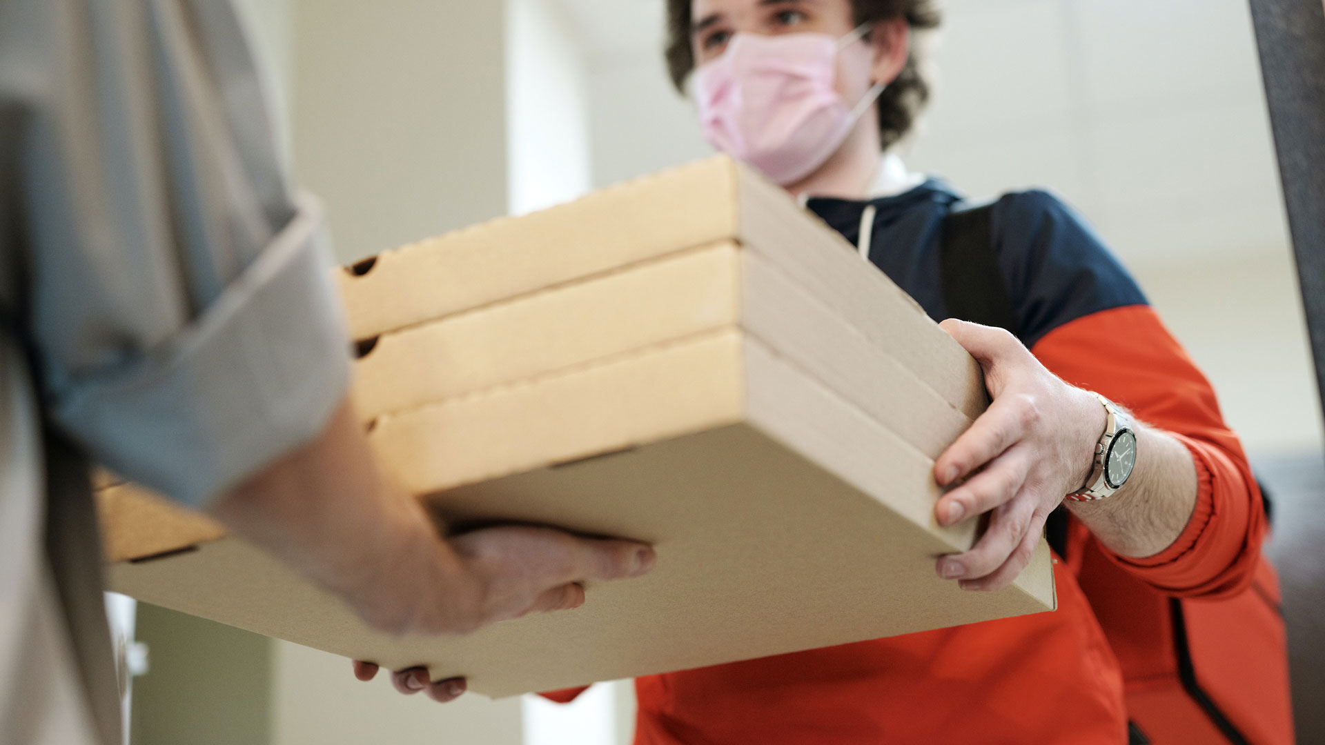 Man in mask delivering pizza boxes