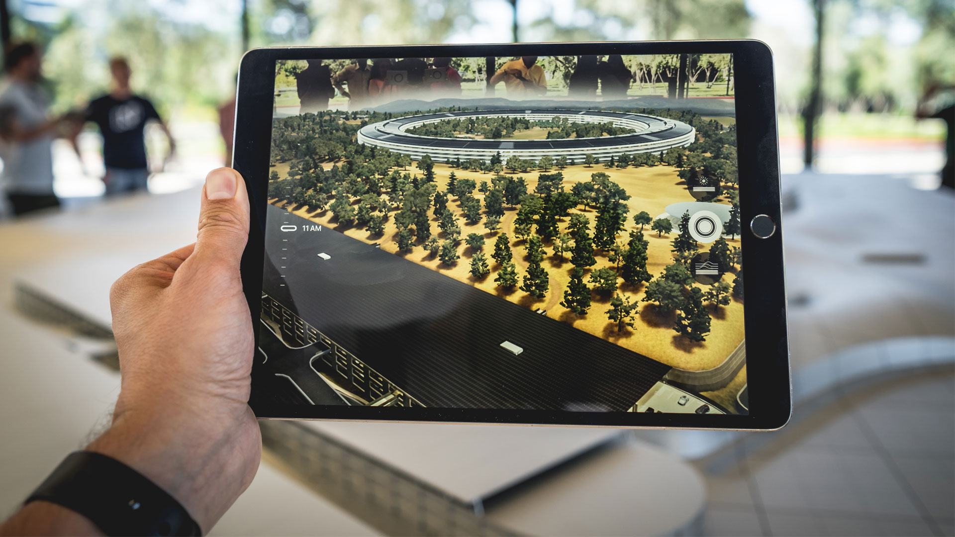 Person's hand holding a tablet device with augmented reality showing development plans for a new building