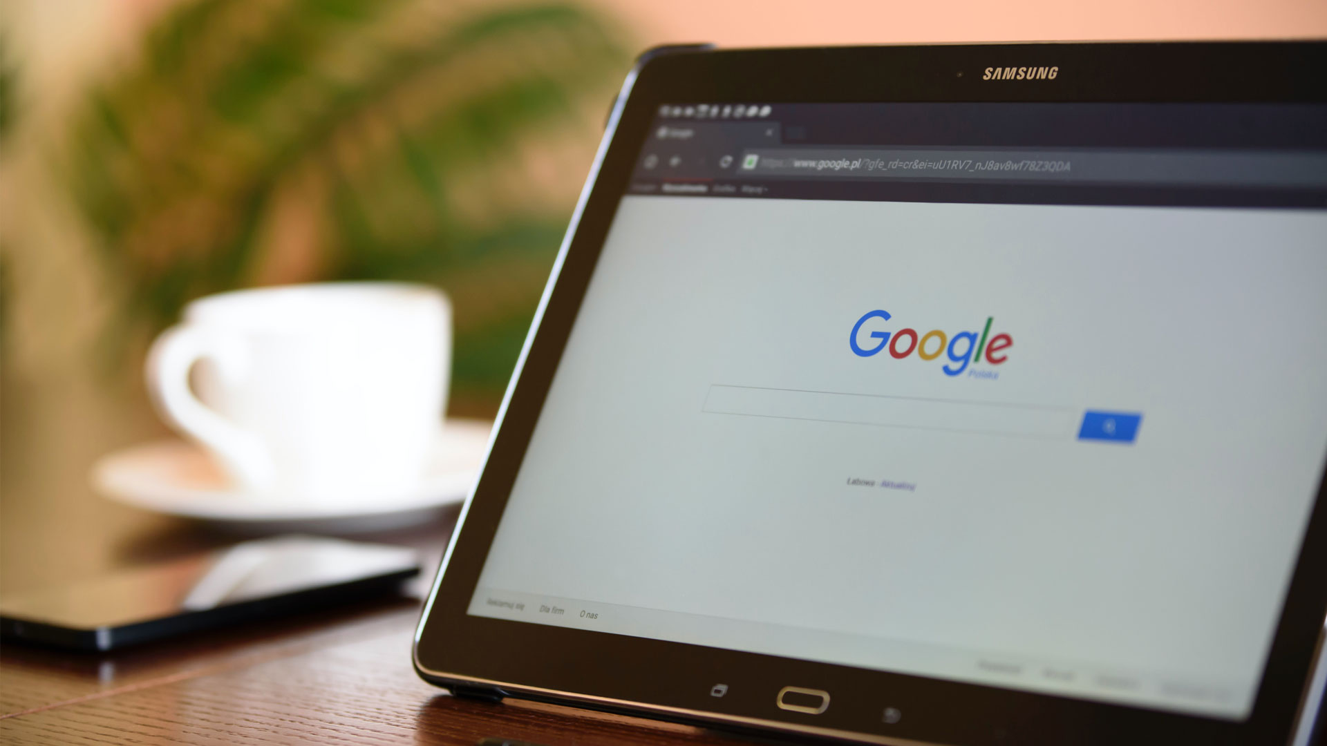 Tablet device open on Google search, with cup and saucer in the background