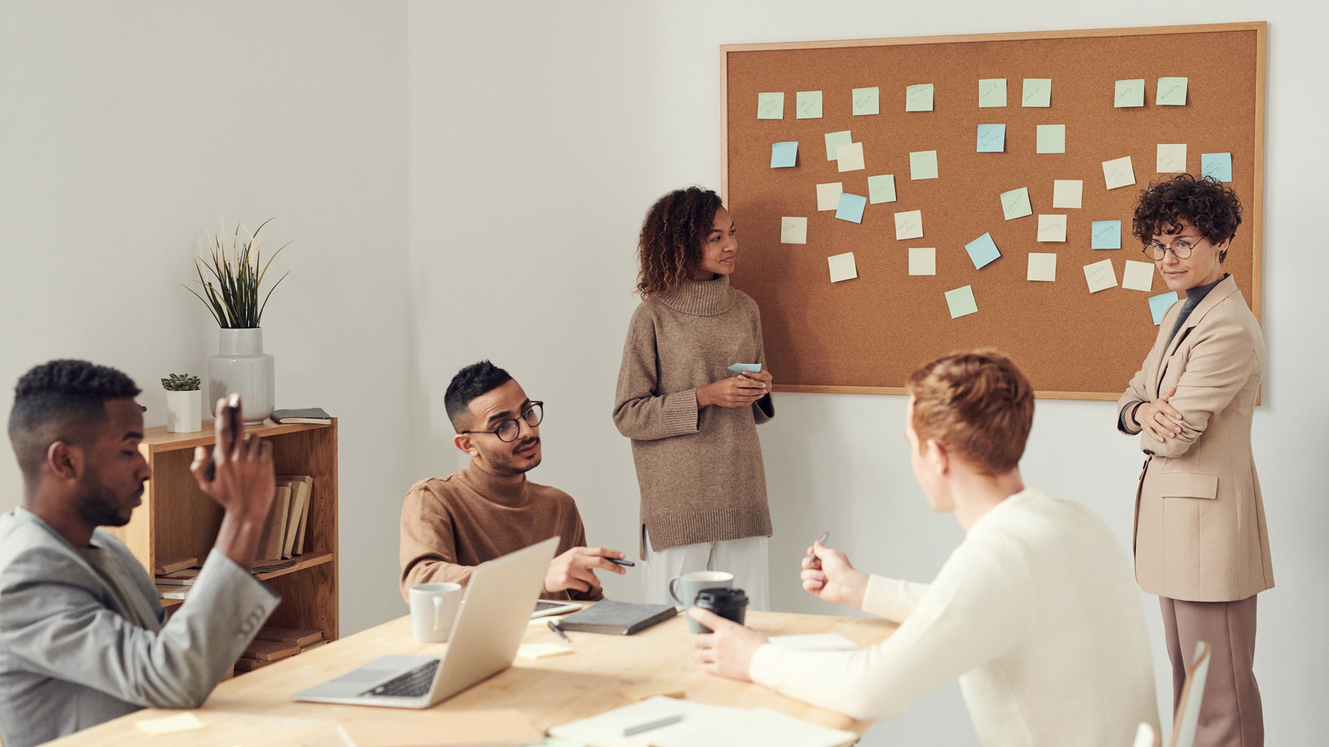 Group of people working around a corkboard with post-it notes