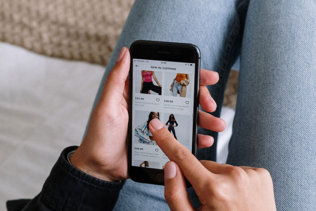 Person using a smartphone and scrolling through a clothing retailer website Woocommerce BoxUK example