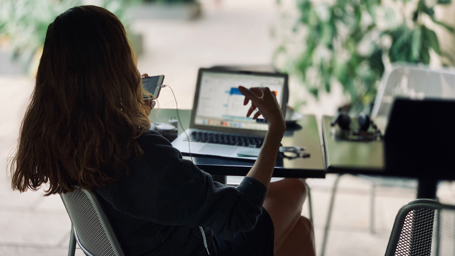 Person using smartphone with laptop on table in background