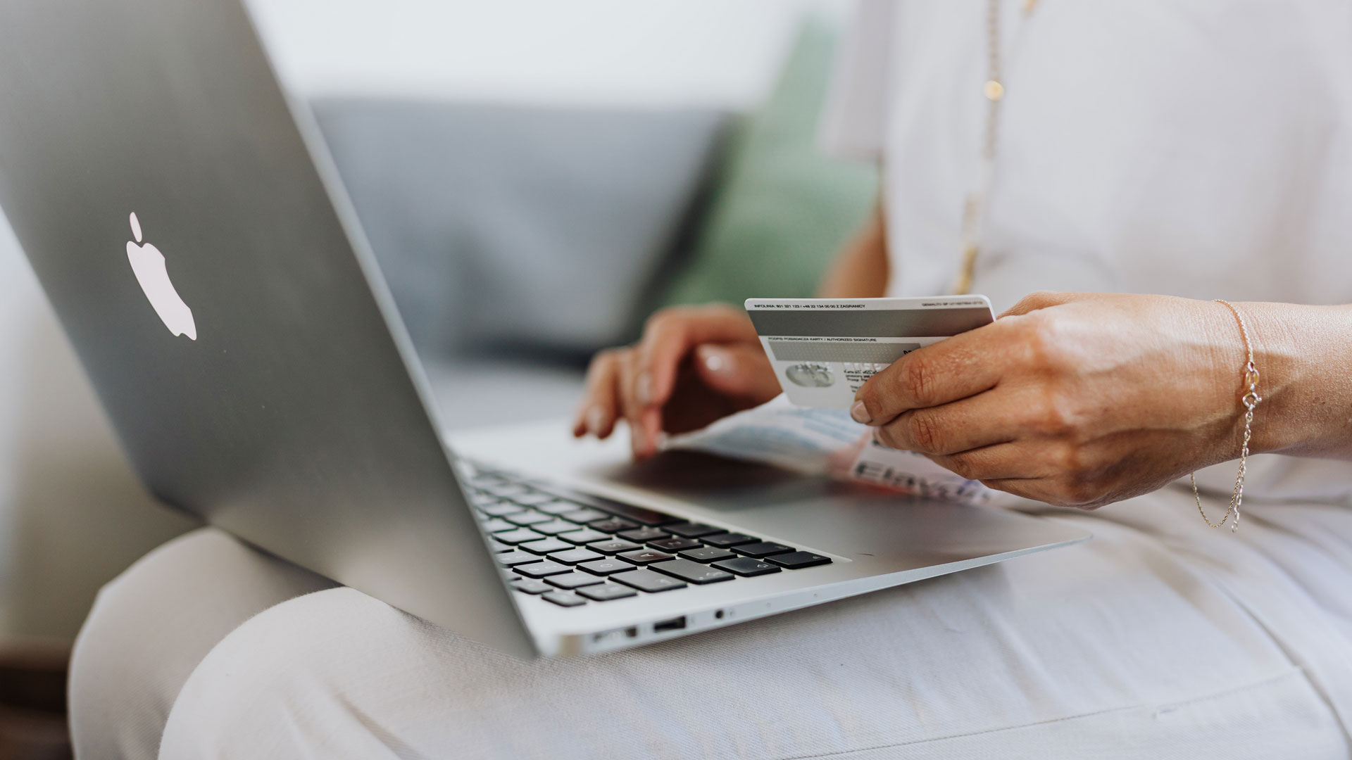 Closeup of person's hand with credit card, in front of laptop