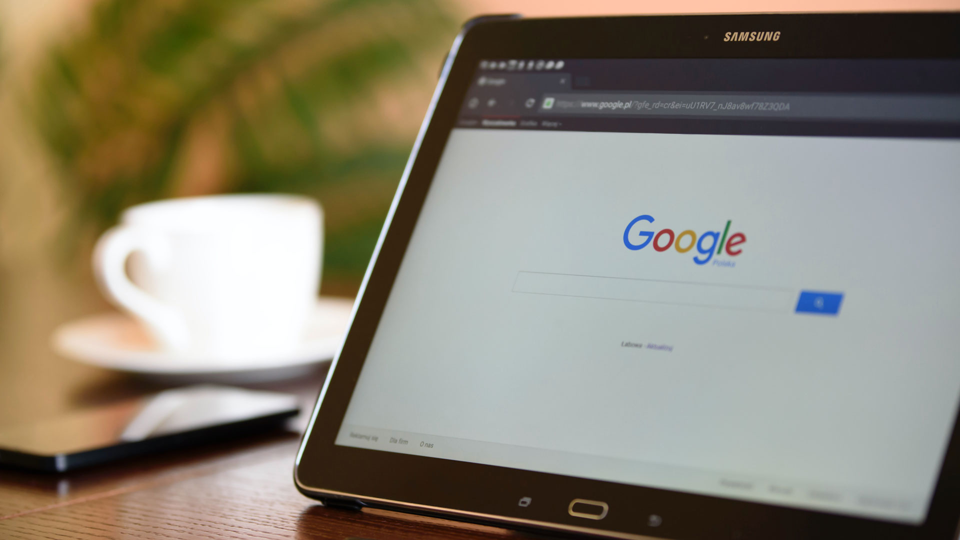 Tablet device open on Google search, with cup and saucer in the background