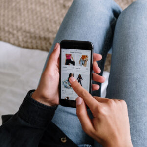 Person using a smartphone and scrolling through a clothing retailer website