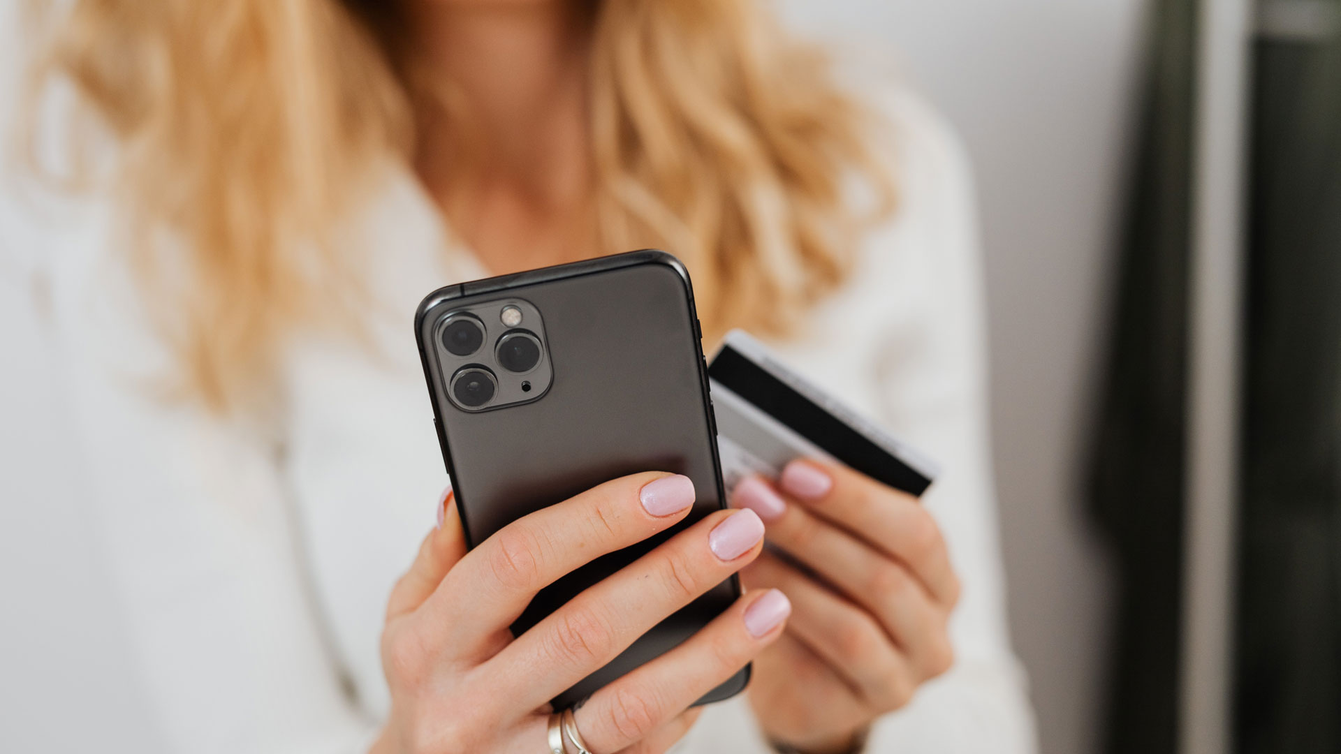 Shot of person using smartphone with credit card in their other hand