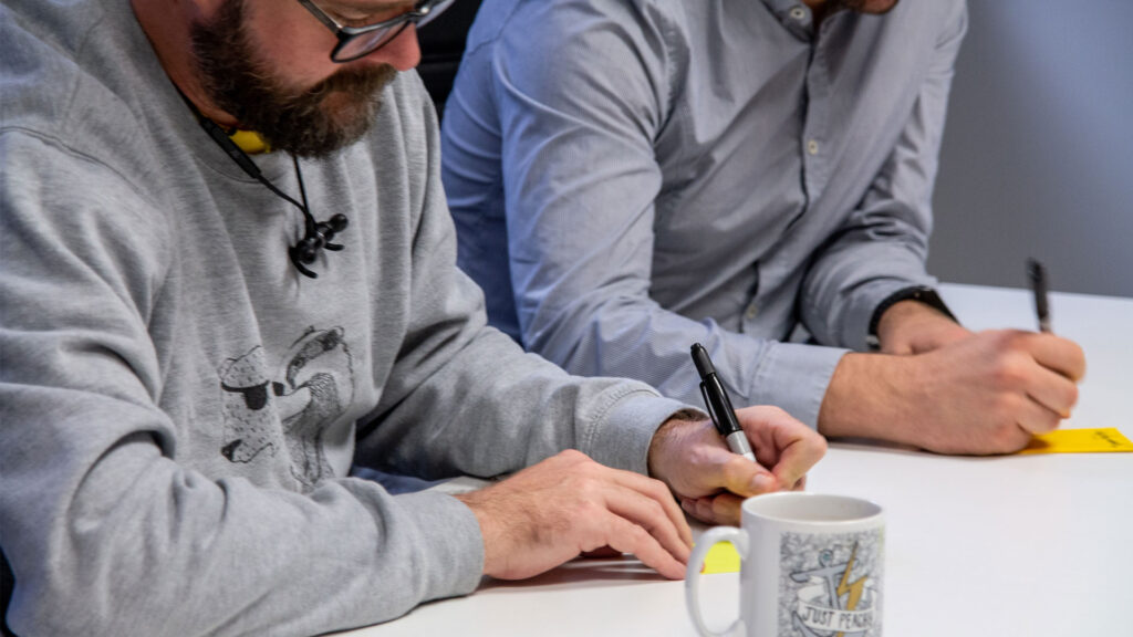 Two people writing on post-it notes
