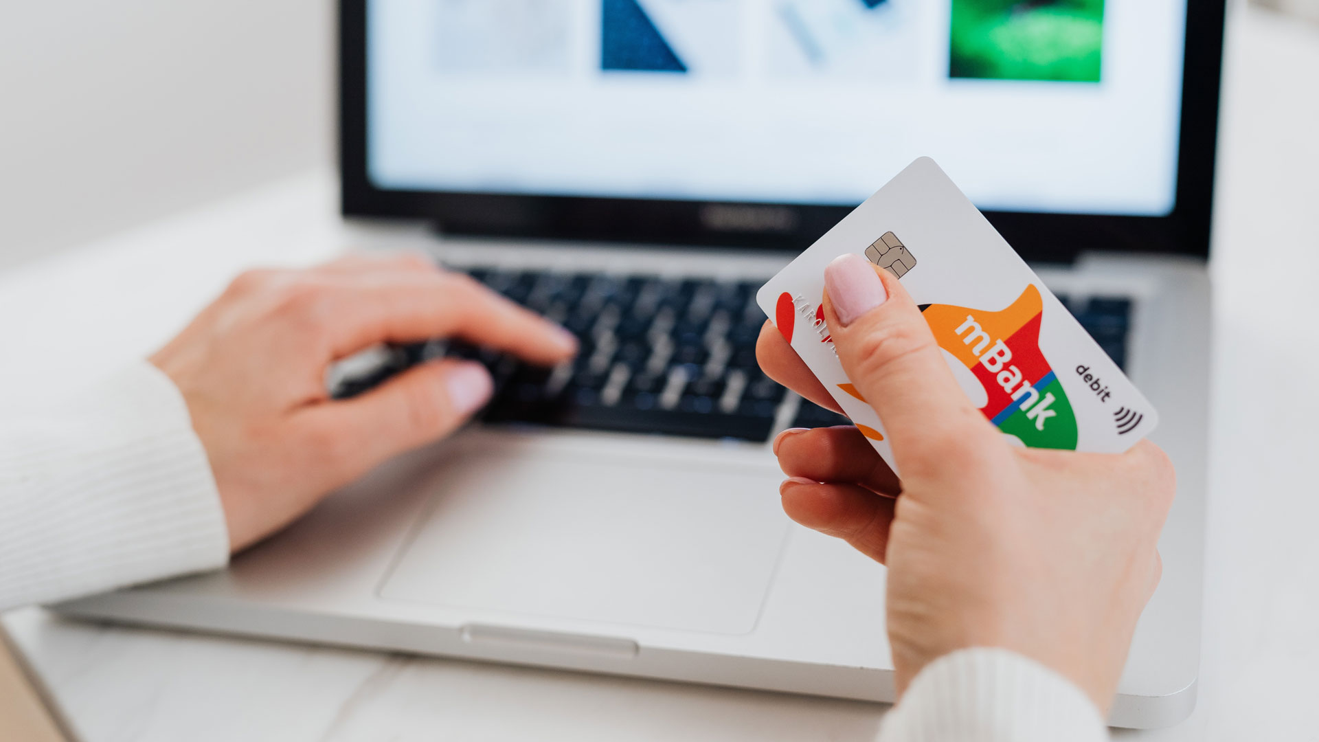 Close up of person holding credit card and using laptop