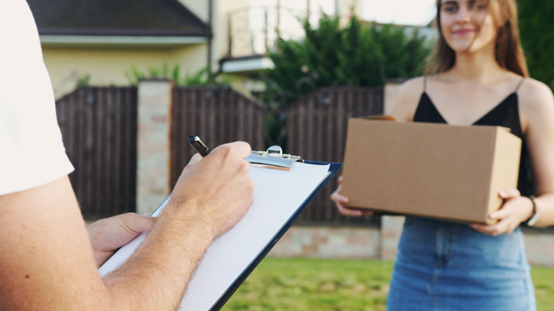 Woman holding delivery box, with person holding clipboard in foreground