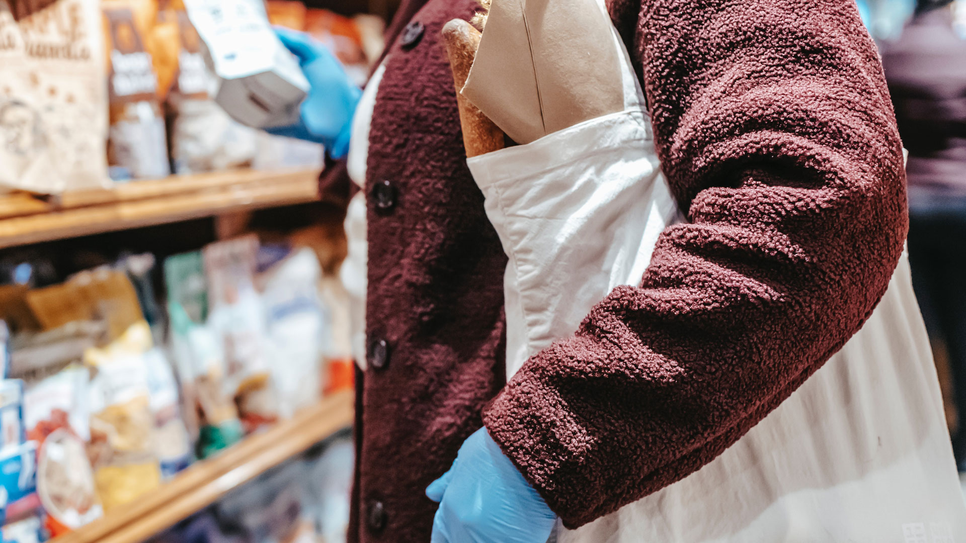 Abstract shot of person browsing food shop, with full tote bag