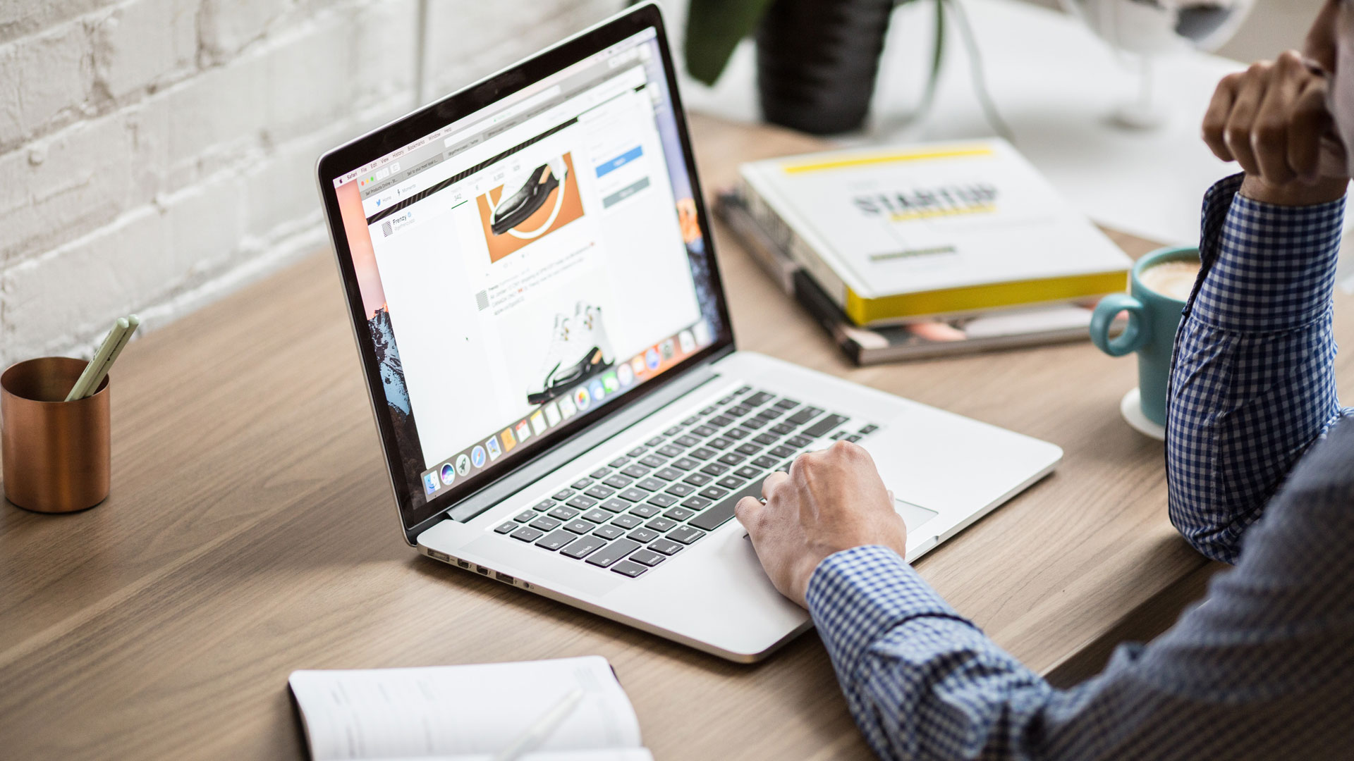 View of a person's arms working on laptop, on wooden desk