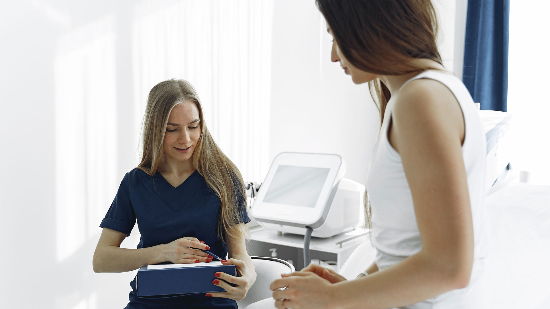 Doctor in consultation with patient sat on a bed