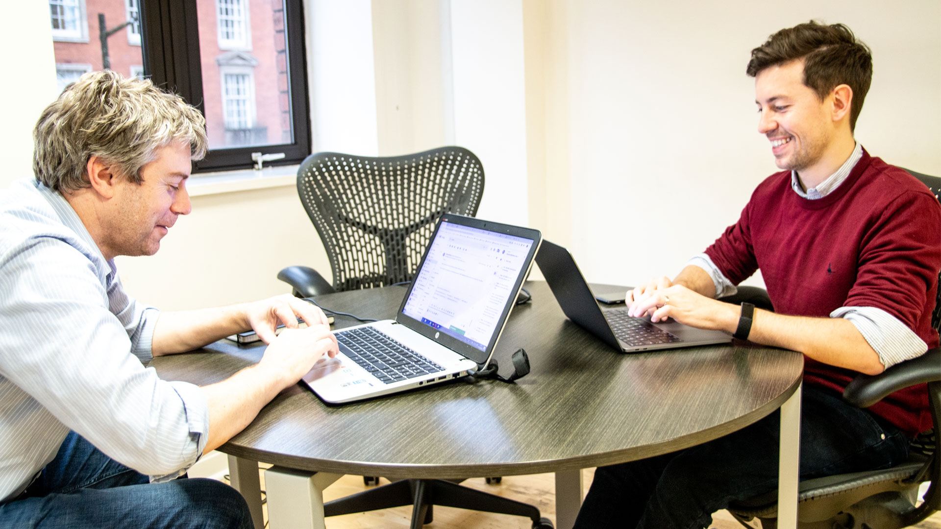 Two people working on laptops at a table