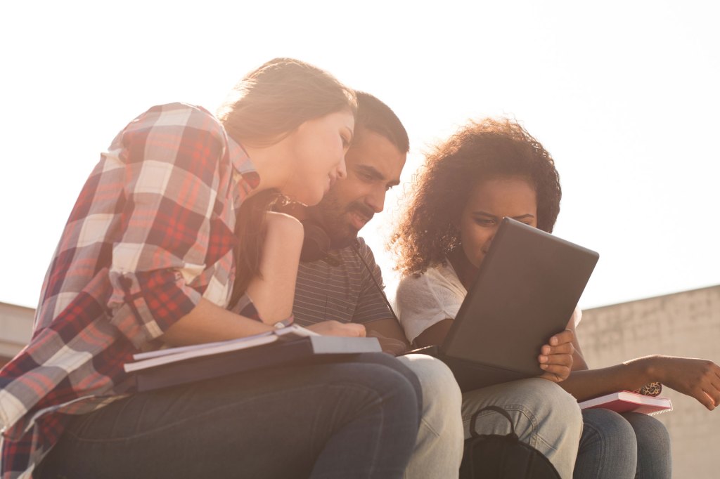 Group of students outdoors looking at a laptop