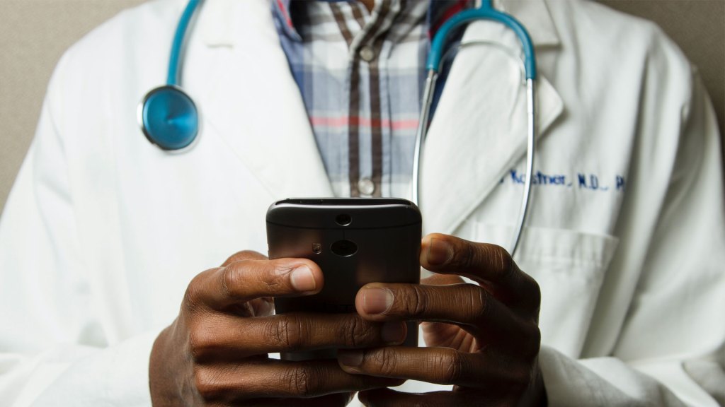 Close up of doctor in a white coat using a smartphone